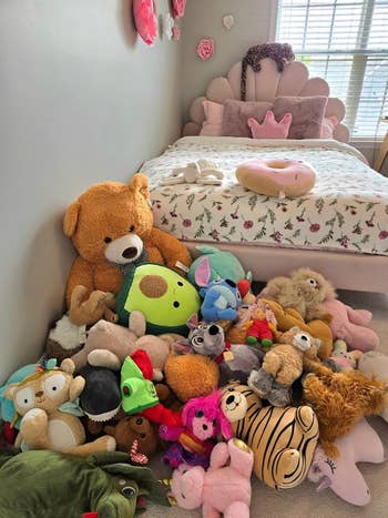 Collection of assorted stuffed animals arranged connected the level adjacent a child's furniture decorated with a crown-shaped pillow, successful a cozy and playful chamber setup
