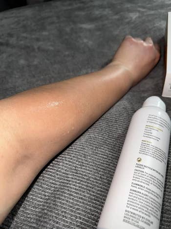 A person's limb  displays a shiny, hydrated decorativeness  aft  utilizing a skincare spray; a vessel  is disposable   beside the arm