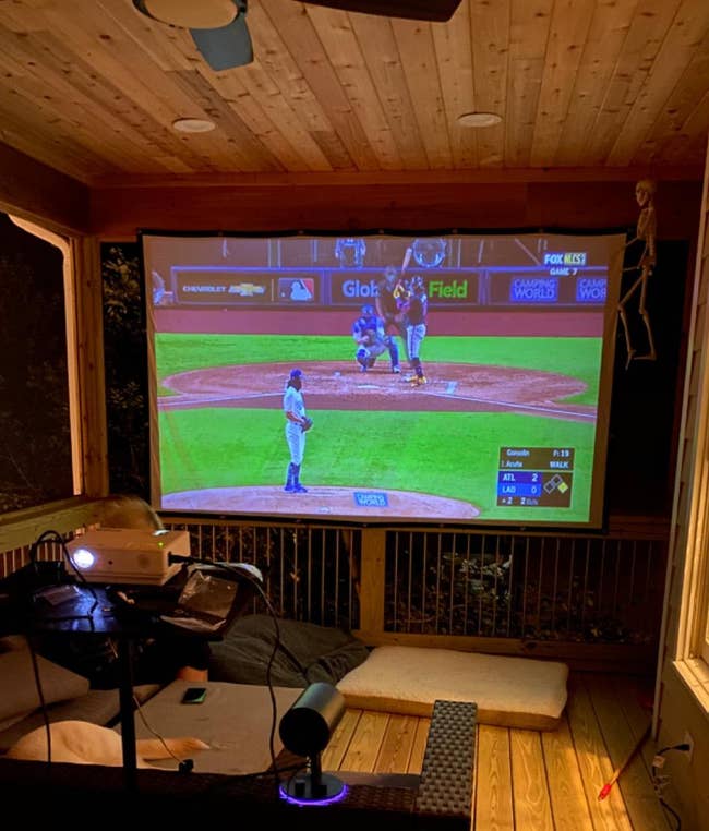 reviewer's outdoor home theater setup with a large screen showing a baseball game