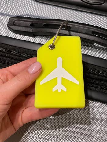 reviewer neon yellow silicone luggage tag on suitcase