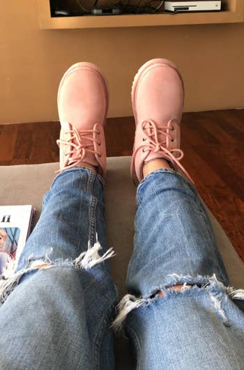 reviewer wearing ugg boots in a light pink color with ripped jeans
