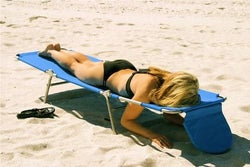 model laying face down on the blue chaise lounge on a beach