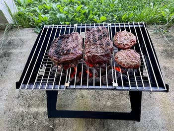 reviewer's grill with burgers and steaks cooking on it