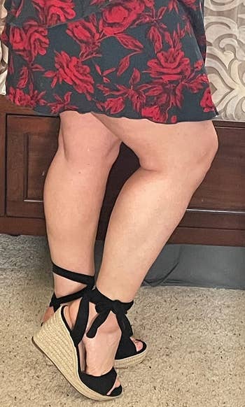 reviewer wearing the black wedges with a floral print dress