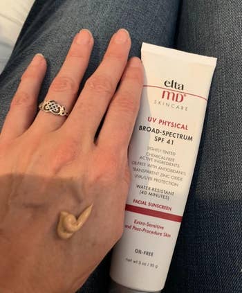 The tan-colored sunscreen on a reviewer's hand