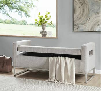 the gray storage bench, slightly open, showing blanket inside