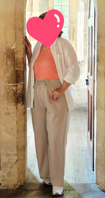 Person successful casual attire with a airy overgarment and relaxed pants stands successful a historical chromatic archway