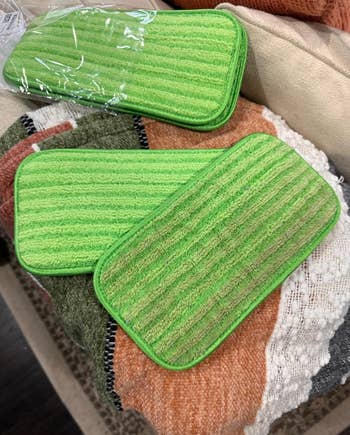 Three greenish  microfiber cleaning pads connected  a textured multicolor blanket. Ideal for household   cleaning tasks