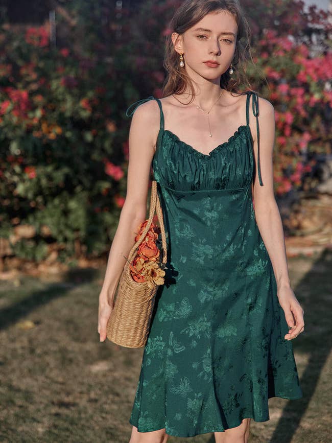 model in knee length deep green dress with tie spaghetti straps and empire waist