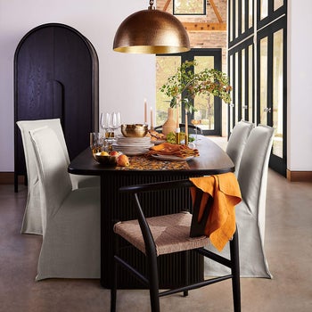Elegantly set dining table with modern chairs, dinnerware, and a centerpiece in a stylish room for a shopping article