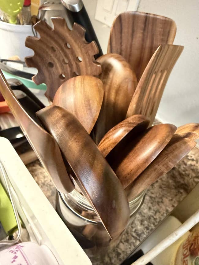 A jar filled with assorted  woody  room  utensils, including spoons, spatulas, and a pasta server, displayed connected  a countertop