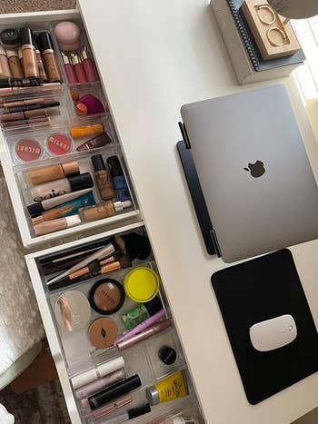 reviewer's desk drawers pulled open to show the clear organizers holding makeup in separate bins