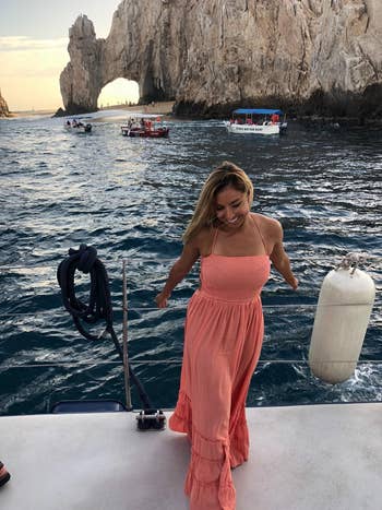 reviewer posing on a boat wearing coral dress
