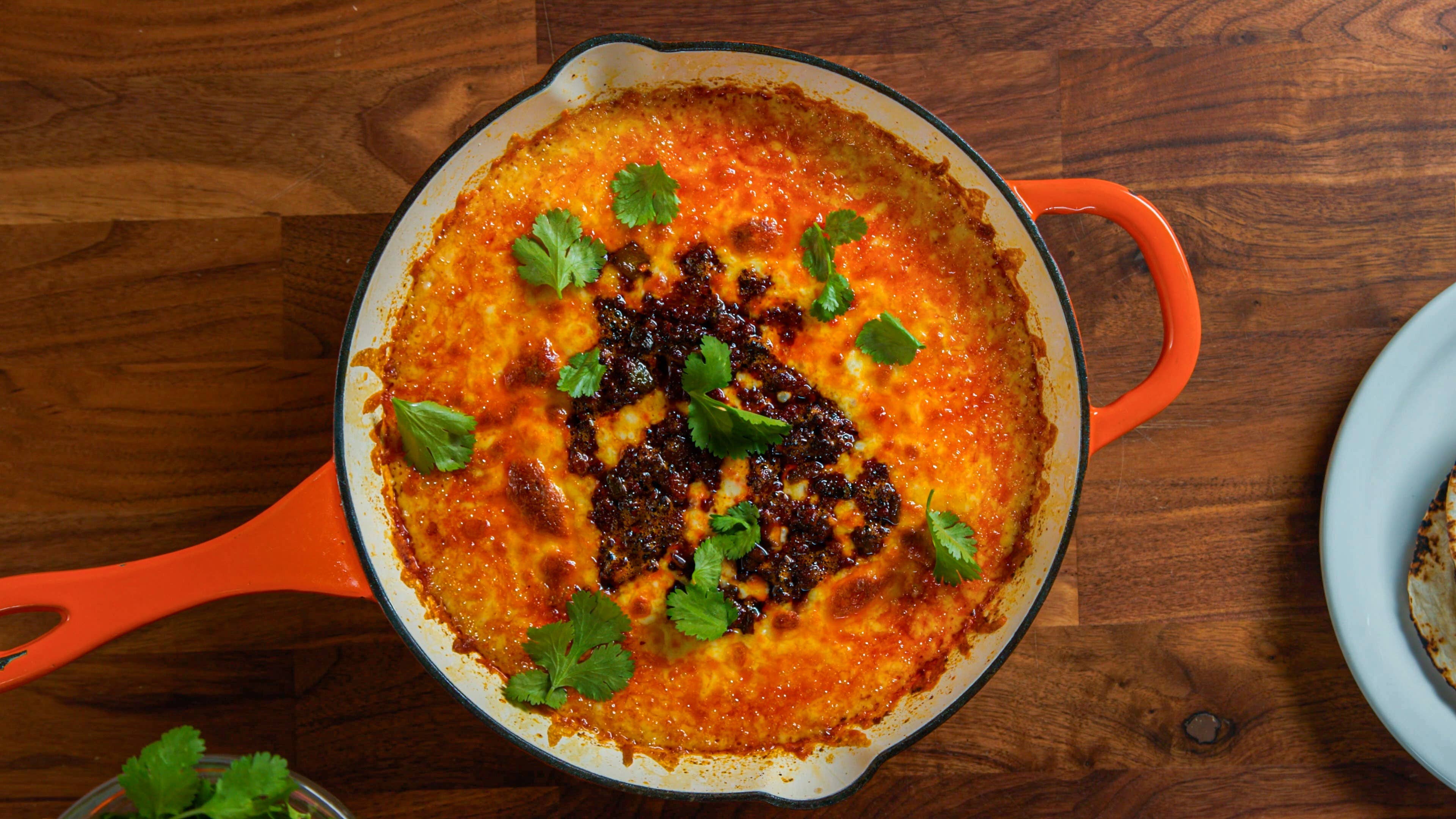 hot skillet of melted cheese topped with golden brown chorizo and fresh cilantro