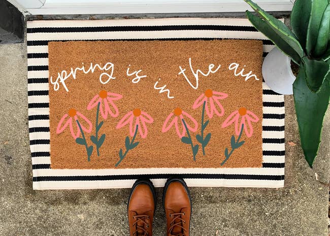 a door mat with pink flowers that reads 