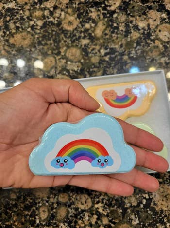 Reviewer holding a bluish  cloud-shaped bath weaponry  with a rainbow sticker connected  apical  and an orangish  and greenish  bath weaponry  disposable   successful  the background