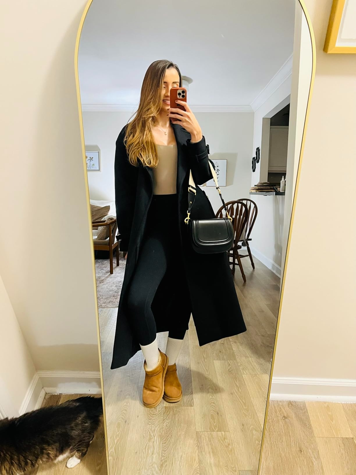 Person taking a reflector  selfie, wearing a agelong  coat, leggings, boots, and carrying a handbag