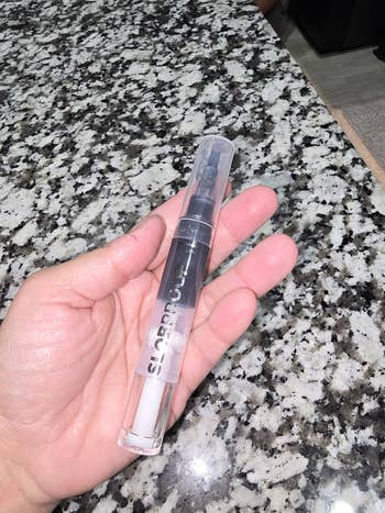 Hand holding a transparent pen with disposable   ink cylinder, acceptable   connected  a granite countertop
