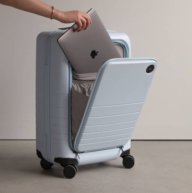 Person packing a laptop into a hard-shell suitcase, ideal for secure travel essentials