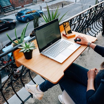 a model working from their laptop on the balcony desk