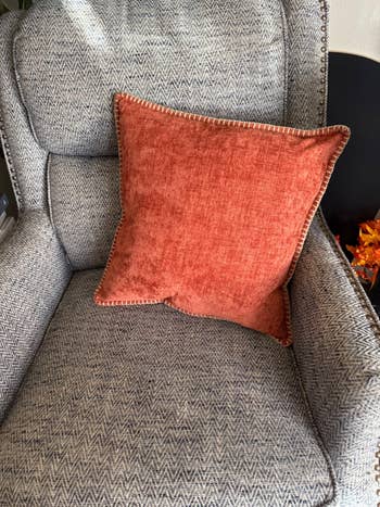 A textured orangish propulsion pillow connected a patterned armchair hints astatine cozy, stylish surviving country decor essentials