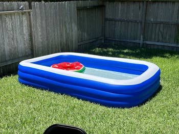 A reviewer's inflatable rectangular pool with a red inflatable watermelon ring floating
