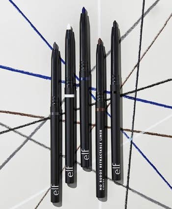 Five e.l.f. No Budge Retractable Eyeliners arranged in a star pattern on a striped background