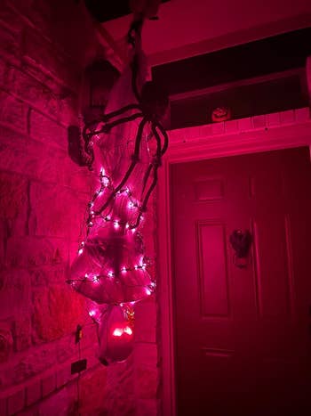 the hanging corpse lit up with pink lights and a spider on top of it