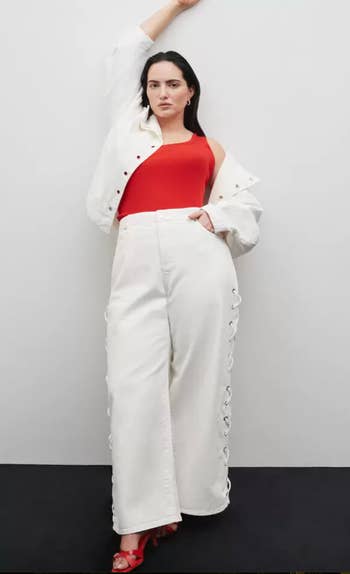 Model in white wide-leg pants with lace-up sides, red top, and white button-up shirt