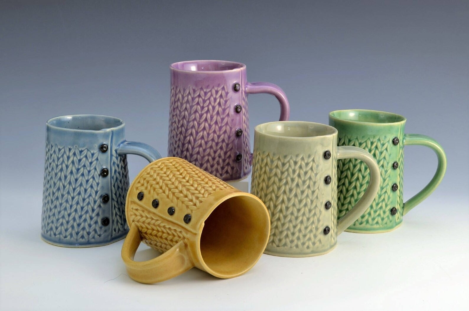 five different colored knitted mugs