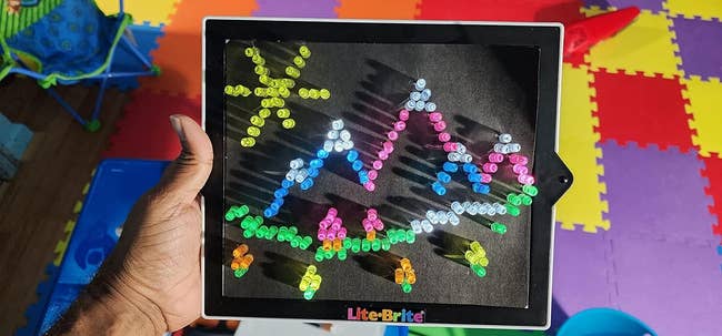 image of reviewer holding up lite brite depicting image of sun and mountains