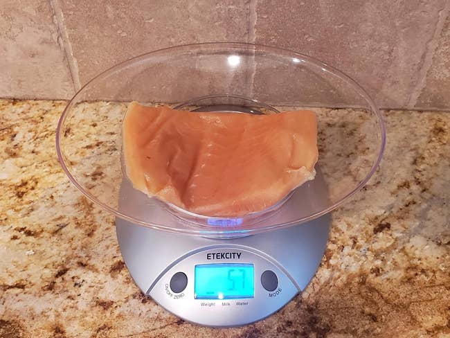 A piece of raw chicken on a digital kitchen scale