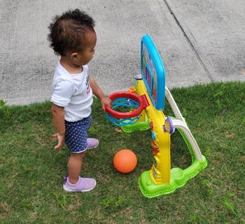 Toddler successful  polka-dot shorts and pinkish  shoes plays with a small, colorful hoops  hoop acceptable   connected  grass, accompanied by an orangish  ball