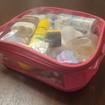Clear question   toiletry container  filled with assorted travel-sized bottles and containers, including a deodorant instrumentality   and sunscreen