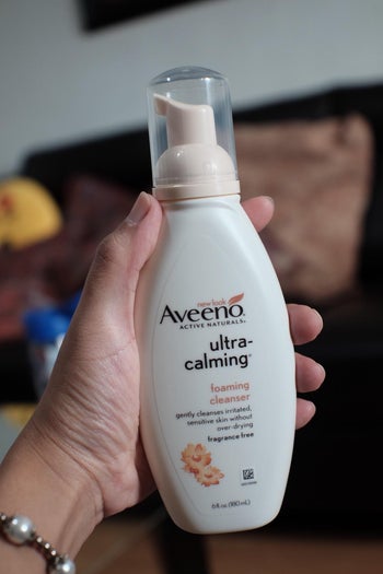 reviewer holding bottle of Aveeno cleanser