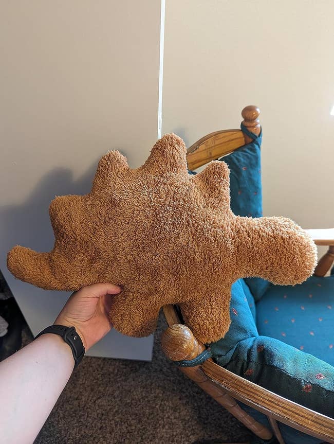 Person holding a stegosaurus nugget plush