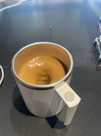 Self-stirring mug with swirling java  inside, connected  a table