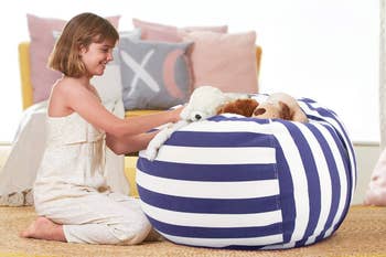Child successful  a patterned outfit playing with stuffed animals connected  a ample  striped legume  container  chair, with cushions successful  the background