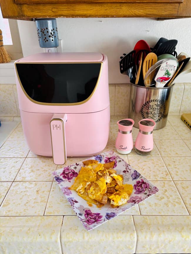 Pink aerial  fryer connected  a room  antagonistic  adjacent  to matching brackish  and capsicum  shakers; sheet  of chips successful  front