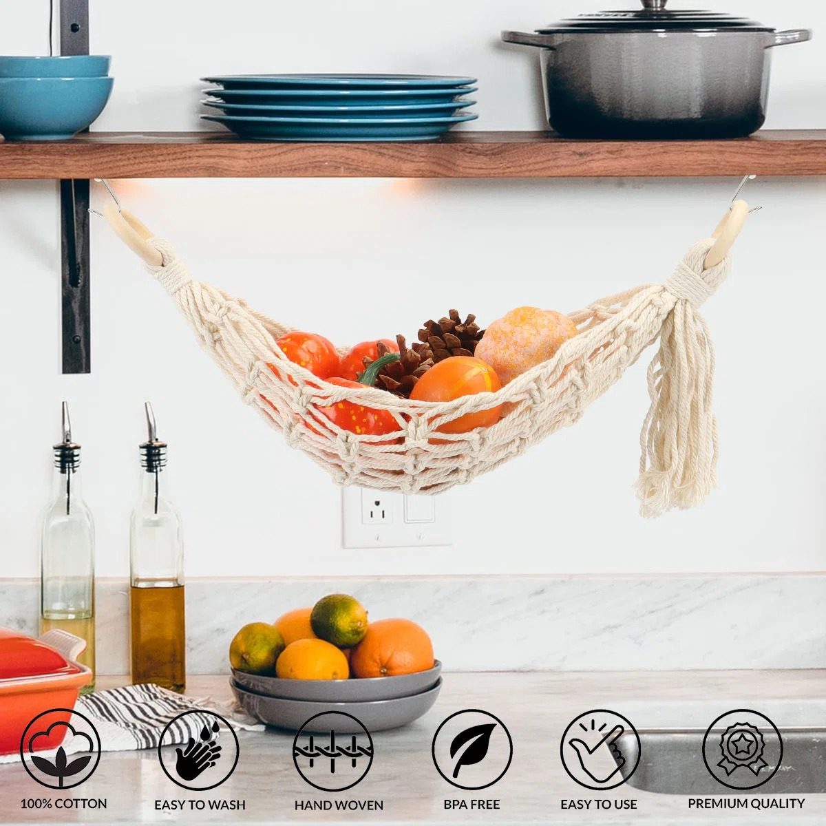 Hanging woven produce hammock under a kitchen shelf, filled with fruits and vegetables. Icons highlight features: 100% cotton, easy to wash, hand woven