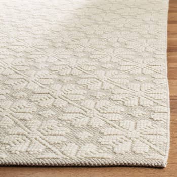 An ivory rug with pop up white flower print on it 