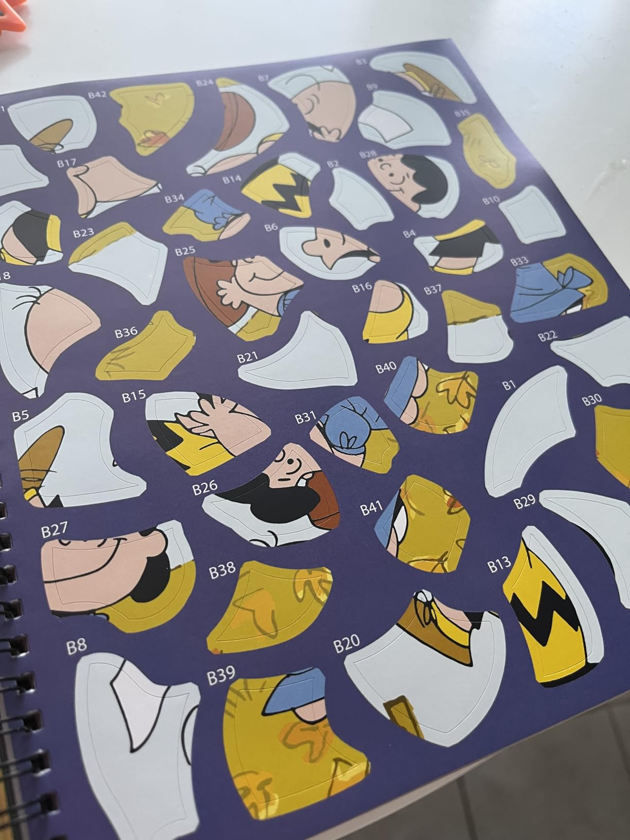 Puzzle pieces featuring cartoon quality  outfits and faces connected  a sheet, with letters and numbers labeling each   piece
