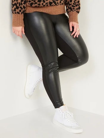 一个模型与人造皮革镶黑色紧身裤的穿着前面板和纬平针织物在后面