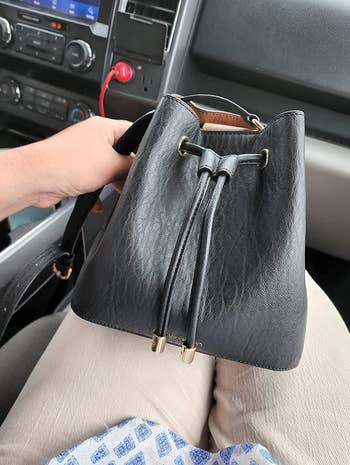 a reviewer holding the mini bucket bag in black