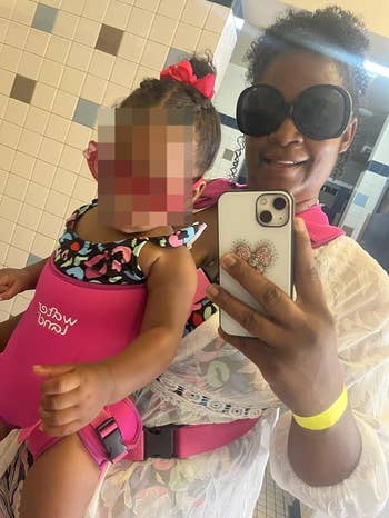 Adult reviewer wearing pink baby carrier with a 14-month-old child inside