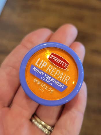 Reviewer holding the tin of balm