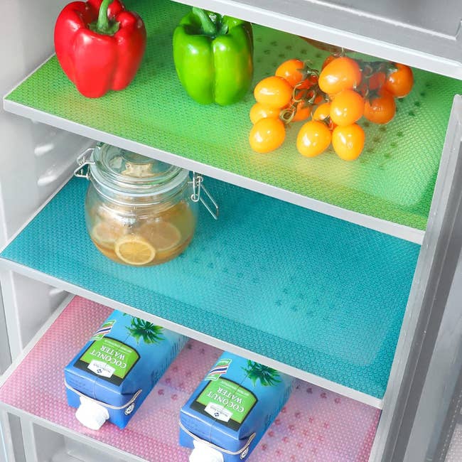 Refrigerator shelves organized with food items and colorful liners
