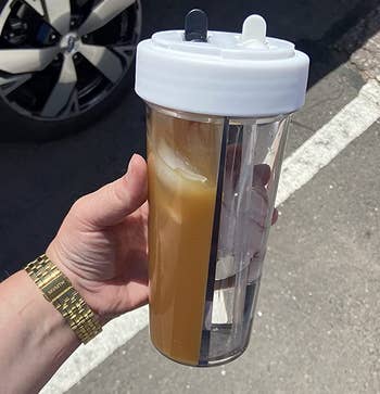 clear plastic water bottle cup with one side full of coffee and the other with water