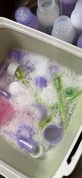 A reviewer's bucket filled with soapy h2o and assorted babe vessel parts being cleaned