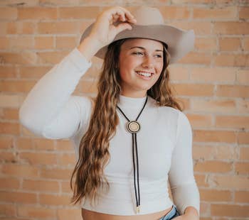 model wearing the bolo tie with a white shirt, hat, and jeans
